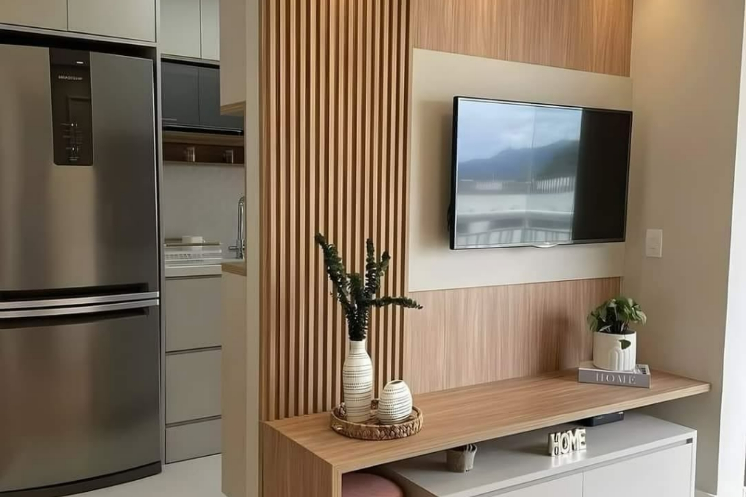 Custom slatted wood TV wall and floating shelf beside a kitchen