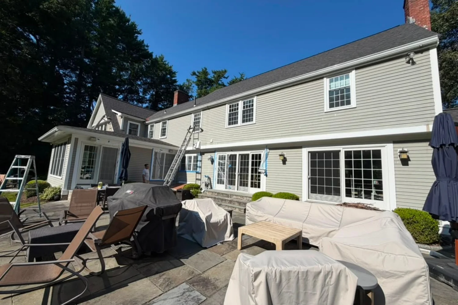 Rear exterior of a two-story home with light siding during exterior work