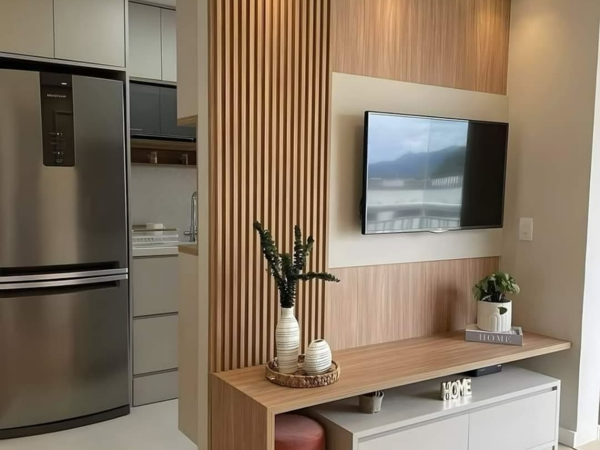 Finished interior with a custom slatted wood TV wall next to a kitchen