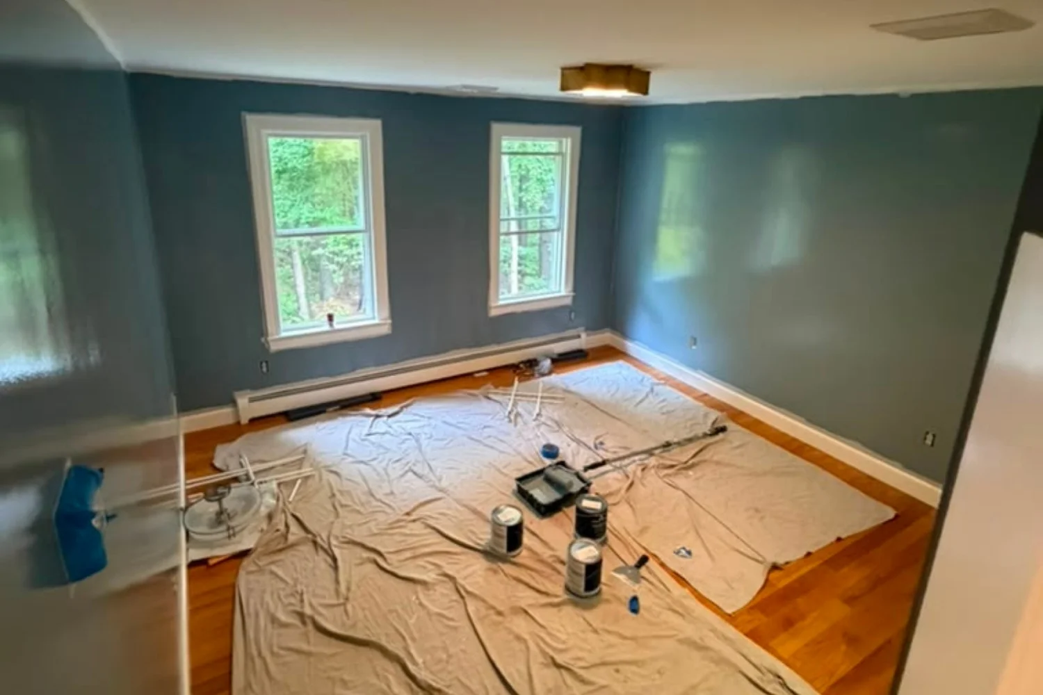 Bedroom with freshly painted deep blue walls and drop cloths covering the floor